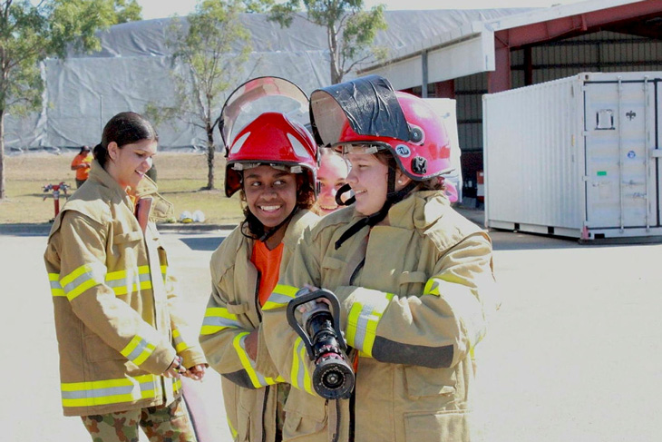 Indigenous students smiling while carrying a fire hose