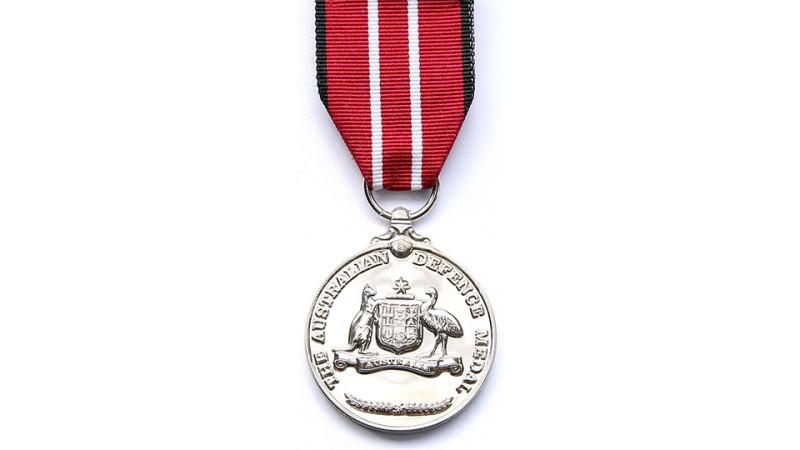 A silver medal with white vertical stripes on red ribbon