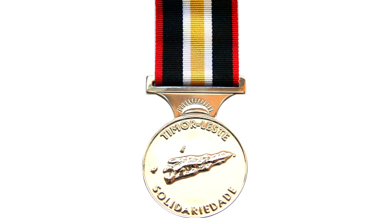 Silver medal with red, black, white, and gold striped ribbon and engraved design