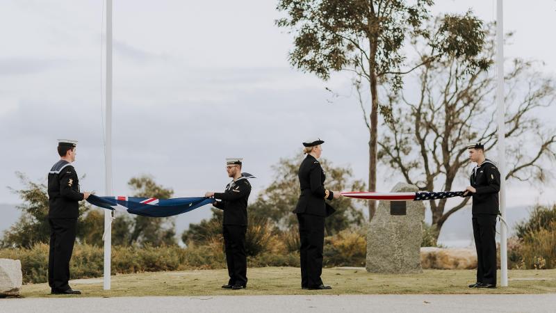 Members of HMAS Farncomb ship’s company fold the national flags of Australia and the United States at the memorial event held in Albany, Western Australia. Photo: Lee Griffith 