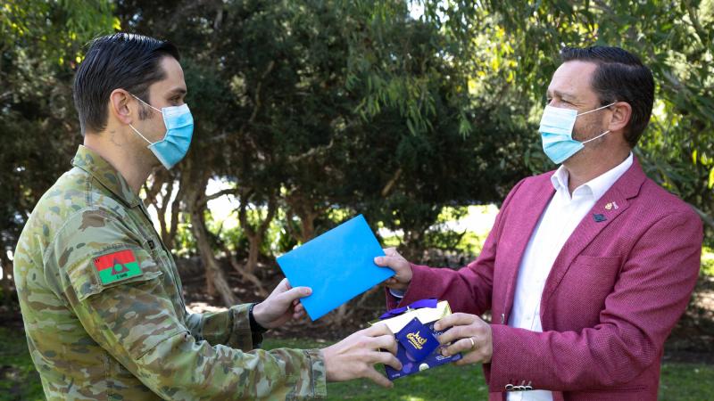 Captain Corey Anderson, of 2nd General Health Battalion, receives chocolates for Father's Day from RSL Victoria Chief of Veteran Services Adam “Buzz” Lawson during Operation COVID-19 Assist in Victoria. Photo: Private Olivia Cameron
