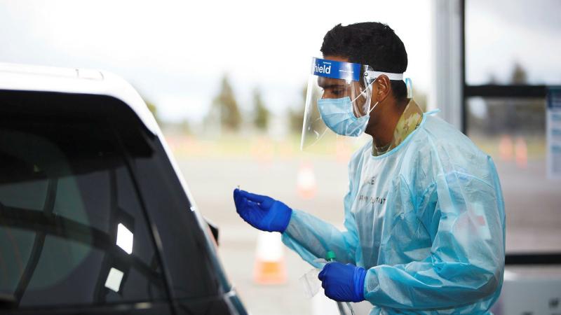 Captain Marcelene Perera takes a COVID-19 test from a member of the public at the Casey Fields COVID-19 community drive-through screening clinic in Victoria. Photo: Private Dustin Anderson