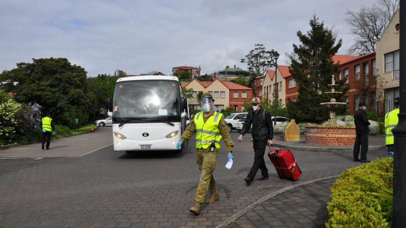 An Army reservist escorts an international arrival heading into quarantine in Hobart.