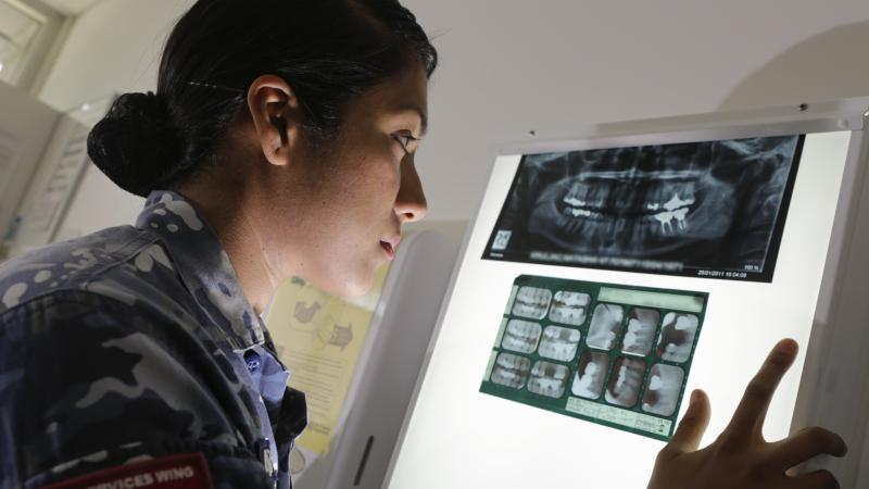 Air Force dentist Squadron Leader Ajitha Sugnanam examines X-rays at Health Services Wing, RAAF Base Amberley. Photo: Corporal Jesse Kane
