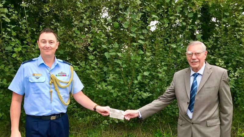 Assistant Air Force Adviser London Wing Commander Leigh Dunnett receives the photo of a No.466 Squadron Wellington Bomber crew from the aircraft’s Rear Gunner Mr Edward Sheriff.