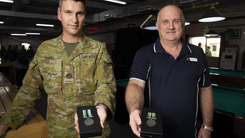 Warrant Officer Class 1 Jason Randell, left, and Luke Collison display their respective military and civilian Australian Operational Service Medals at Australia’s main operating base in the Middle East region. Photo: Corporal Tristan Kennedy