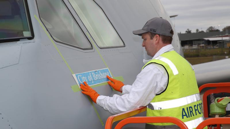 Corporal David Abello, of No. 33 Squadron, prepares to paint the name City of Brisbane onto KC-30A A39-002 at RAAF Base Amberley. Photo: Corporal Colin Dadd