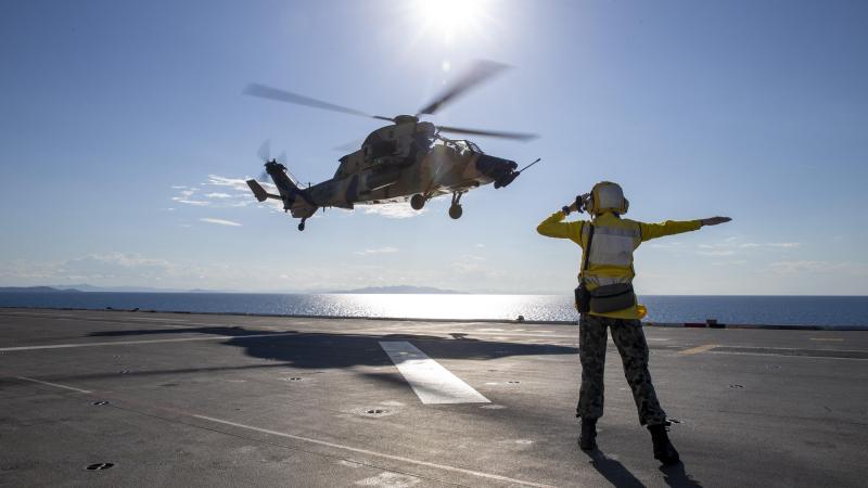Able Seaman Lily Hardin waves off an Army ARH-Tiger as it takes off from the deck of HMAS Adelaide near Townsville during Exercise Sea Wader. Photo: Leading Seaman Nadav Harel
