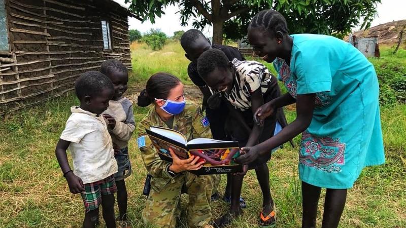 Captain Stephanie Palfrey–Sneddon shows school children in South Sudan her book Young Voices of South Sudan.