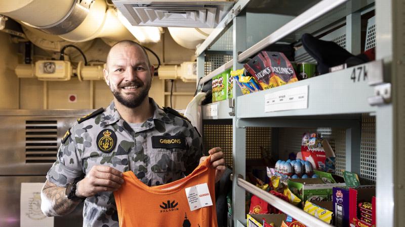 Leading Seaman Luke Gibbons with some of the merchandise in HMAS Arunta's canteen. Photo: Leading Seaman Jarrod Mulvihill