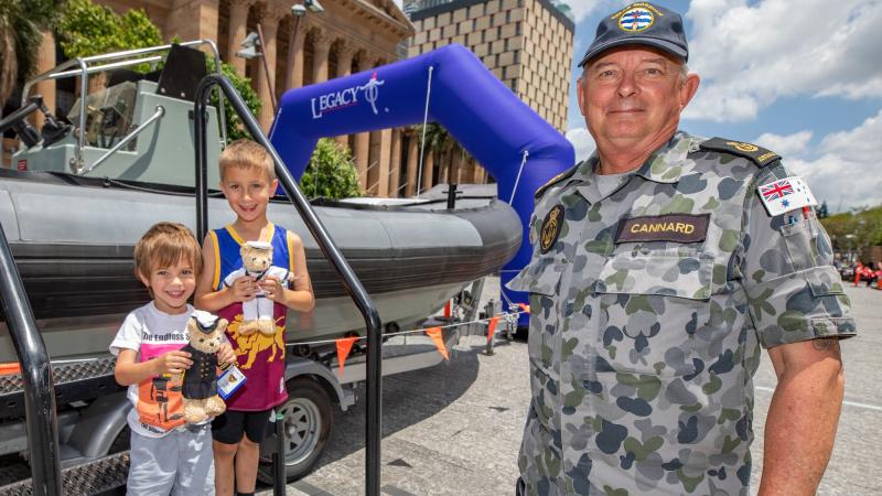 Chief Petty Officer Paul Cannard of HMAS Moreton with Luka and Kai at the Rigid Hull Inflatable Boat display at King George Square, Brisbane. Photo: Corporal Jesse Kane