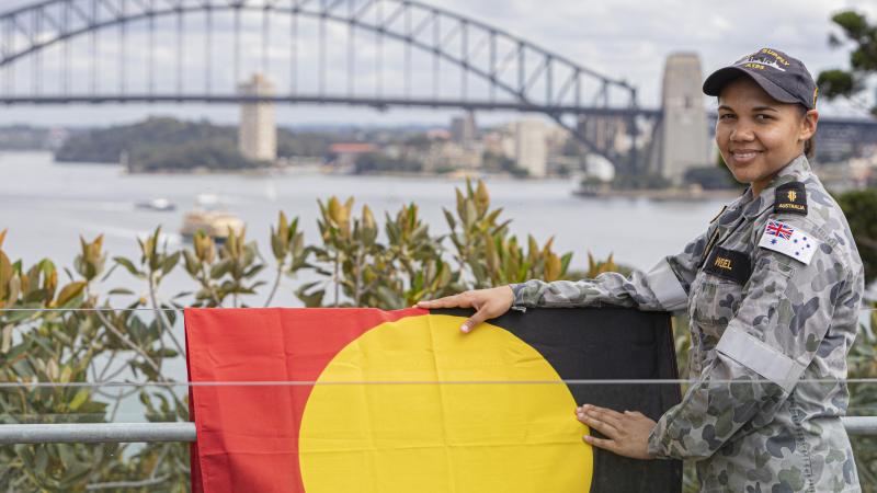 Able Seaman Boatswain's Mate Jahlaya Weazel with the Australian Aboriginal Flag at HMAS Kuttabul, Sydney. Photo:  Able Seaman Benjamin Ricketts