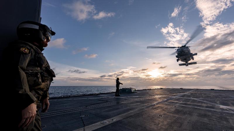 Lieutenant Commander Matthew Schroder, left, observes the departure of a US Navy MH-60R from HMAS Ballarat's flight deck during Exercise Malabar. Photo: Leading Seaman Shane Cameron 