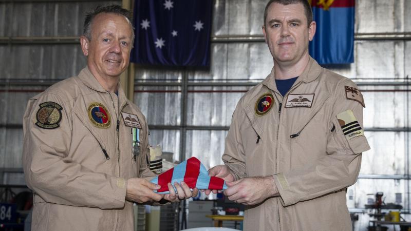 Outgoing Commander Air Task Group 630 Wing Commander Darren Lines, left, passes the Commander's Pennant to incoming commander, Wing Commander Alastair Robertson, at Australia's main operating base in the Middle East region. Photo: Sergeant Ben Dempster