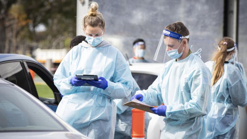 Private Luke Edwards, from the 3rd Battalion, Royal Australian Regiment, right, helps paramedic Kayla Brouwer at a drive-through COVID-19 test clinic in Melbourne during Operation COVID-19 Assist. Photo: Corporal Daniel Strutt