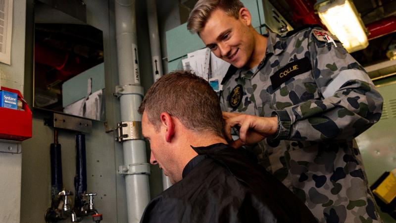 Commander Antony Pisani gets his hair cut by Able Seaman Steven Collie while on the Indian Ocean Deployment. Photo: Leading Seaman Shane Cameron