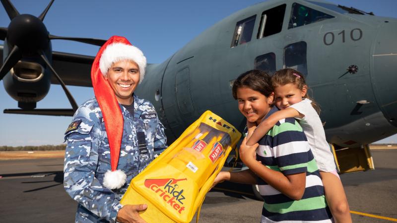 No. 27 Squadron Indigenous liaison officer Flight Lieutenant David Williams hands a gift to Mya and Aria Richards at Charleville during Exercise Christmas Hop. Photo: Corporal Jesse Kane
