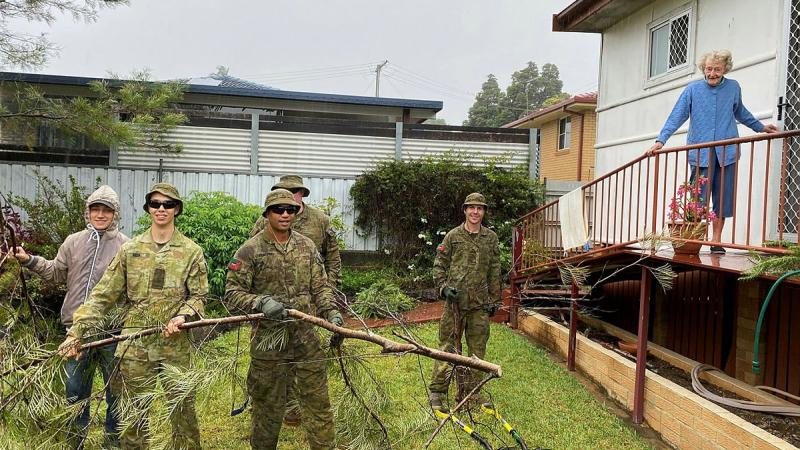 Connor Nish, left, and 41st Battalion, Royal New South Wales Regiment, soldiers Private Callum Nish, Private John Koronui, Corporal Paul Kohlhagen and Private Tom Mackney remove branches from Myrie McPherson’s backyard.