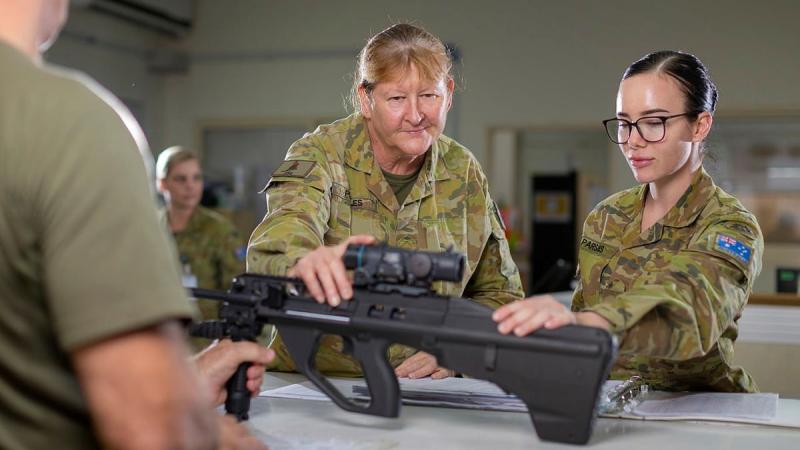 Warrant Officer Class 2 Cheryl Peebles, centre, with a soldier signing out a weapon from the armoury at Camp Baird in the Middle East region. Photo: Corporal Tristan Kennedy