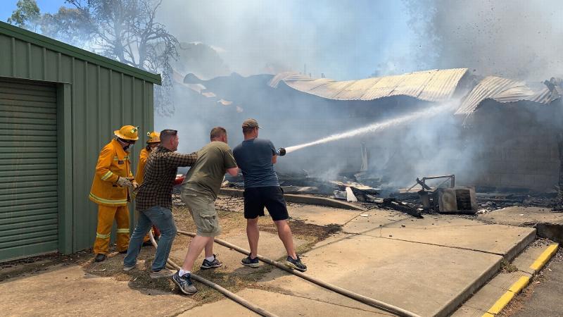 Combined Arms Training Centre soldiers Major John Ozols, left, Major Matt Whitwell and United States Marine Corps Gunnery Sergeant Ryan Accornero help firefighters battle a blaze at Puckapunyal Primary School on December 6 last year.