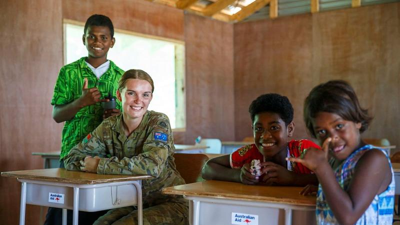 Army’s 2nd General Health Battalion’s Private Edie Haley with local children in the repaired and refurnished Galoa Island Primary School, Fiji. Photo: Corporal Dustin Anderson