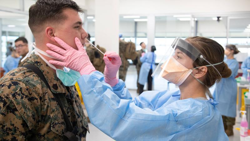 A Royal Australian Navy Medic from ADF Joint Health Unit - Central Australia takes a swab as part of pre-quarantine health screening for recently arrived US marines at RAAF Base Darwin. Photo: Petty Officer Peter Thompson