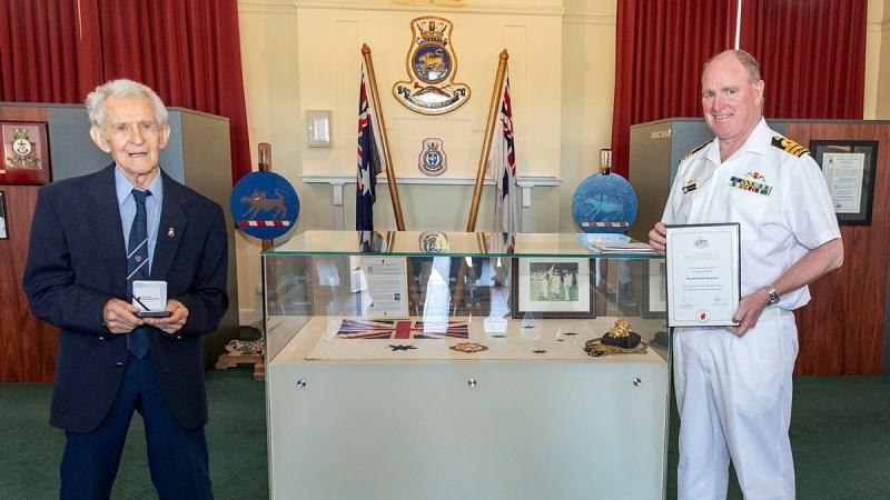 Former Able Seaman Ronald Bergman, 94, is presented a World War II 75th anniversary commemorative medallion by the Executive Officer HMAS Cerberus Commander Martin Holzberger during Mr Bergman’s visit to the base. Photo: Leading Seaman James McDougall