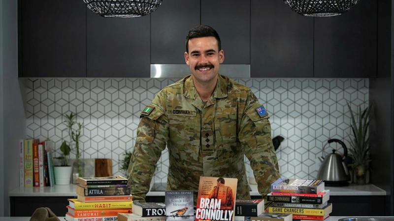 Captain Dylan Conway, of the 6th Battalion, Royal Australian Regiment, with books he read while bed-ridden after surgery. He later recommended books to others as part of his initiative, Brothers n' Books. Photo: Private Jacob Hilton