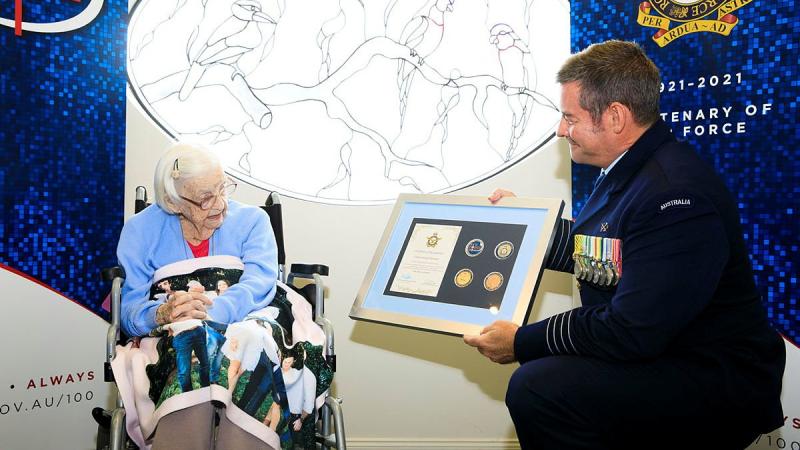 Senior Australian Defence Force Officer RAAF Base Amberley Group Captain Iain Carty presents Air Force veteran Mary Collins with an Air Force 2021 commemorative memento in celebration of her 100th birthday. Photo: Corporal Brett Sherriff