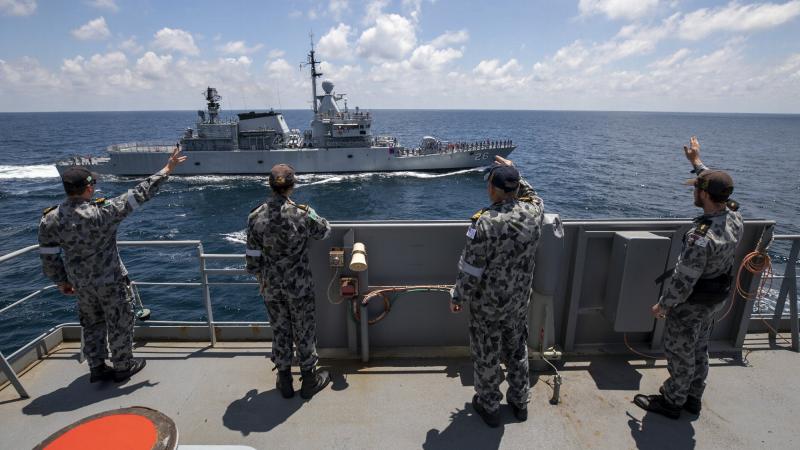 Members of HMAS Sirius’ ship's company wave to the crew of Royal Malaysian Navy ship KD Lekir in the Andaman Sea. Photo: Leading Seaman Thomas Sawtell