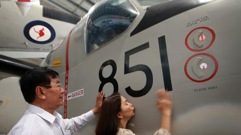 Son Tien Trang Kim and Chi Crosskill touch and kiss the Grumman Tracker. 