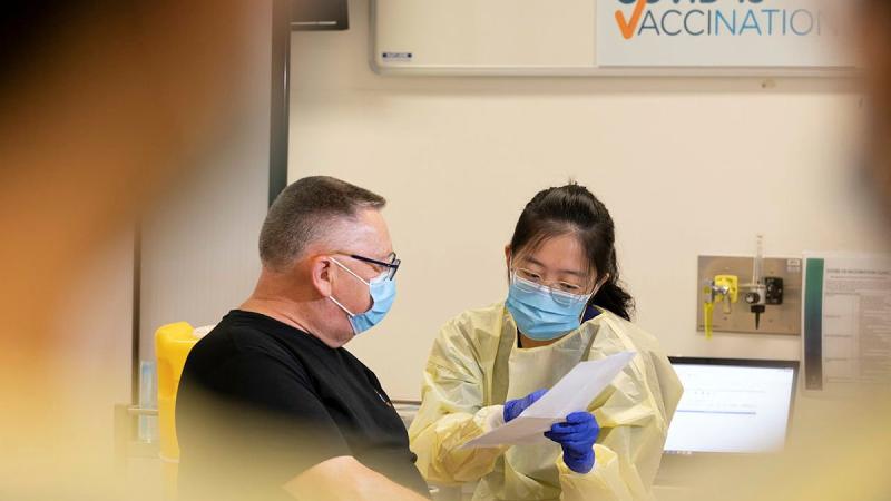 Joint Task Group 629.4 Sergeant Weller discusses post COVID-19 vaccine paper work with registered nurse Mei Goh at the Royal Adelaide Hospital. Photo: Leading Aircraftman Stewart Gould