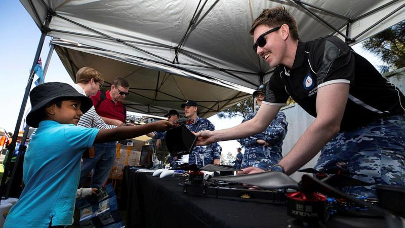 Leading Aircraftman Nathan Thompson of the Air Force Drone Racing Team gives Hawkesbury Show visitor Pranav a closer look at a racing drone. Photo: Corporal David Said