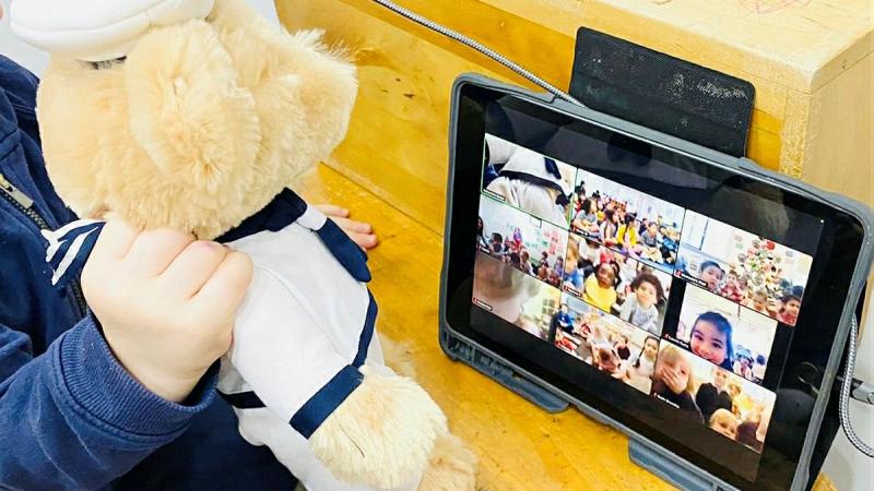 A Navy teddy is held by a child from the Vaucluse Cottage Childcare Centre in Sydney, during a Zoom call to sister preschools. Photo: Emma Wholihan