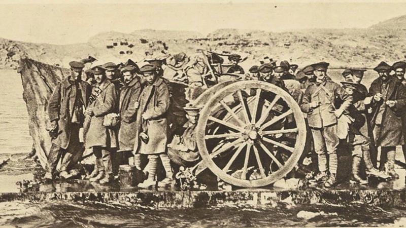 An evacuation raft built by the Royal Australian Navy Bridging Train is shown evacuating artillerymen with a field gun in January 1915. The rafts were towed by lighters during the evacuation from Gallipoli.