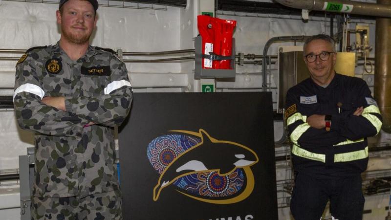Leading Seaman Jackson Setter, left and Navantia Australia engineer Jose Luis Bouza Fernandez stand with a new passageway sign for HMAS Supply. Photo: Able Seaman Benjamin Ricketts 