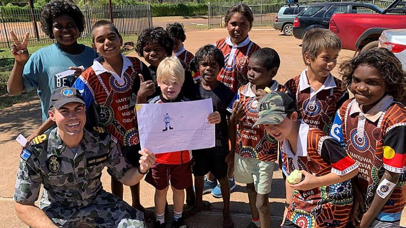 HMAS Coonawarra Officer Lieutenant Matt Dobrincic with students from Borroloola Primary School during Anzac Day community engagement. 