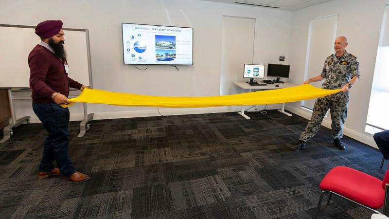 Sikh Gurdwara Perth youth coordinator Prabhjot Singh shows HMAS Stirling Commanding Officer Captain Gary Lawton how to tie a turban during Vaisakhi celebrations. Photo: Leading Seaman Ronnie Baltoft