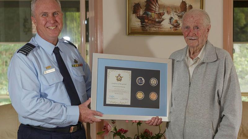 Senior Australian Defence Force Officer for RAAF Base Williamtown Group Captain Anthony Stainton presents George Lincoln an Air Force centenary memento. Photo: Sergeant David Gibbs