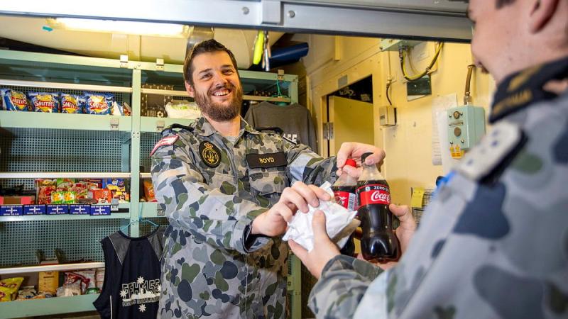 HMAS Ballarat's Assistant Canteen Manager Leading Seaman Timothy Boyd serves Able Seaman Daniel Johnson during deployment. Photo: Leading Seaman Ernesto Sanchez