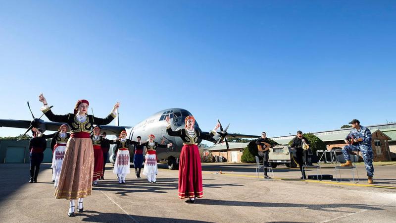 Dancers from the Cretan Association of Sydney perform in front of a C-130J Hercules as No. 37 Squadron avionics technician Leading Aircraftman Yianni Skoulakis, right, plays the laouto at RAAF Base Richmond. Photo: Corporal David Said