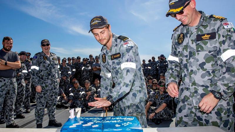 Commanding Officer Ballarat Commander Antony Pisani, right, with the youngest crew member Seaman Christiaan Rijkaart during the cutting of the ship’s birthday cake at sea. Photo: Leading Seaman Ernesto Sanchez