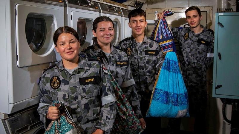 Able Seamen Cerys Zurek and Abbi Greenaway, Seaman Tiago Torres and Able Seaman Richard New display their personalised dhoby bags in the laundry of HMAS Ballarat. Photo: Leading Seaman Ernesto Sanchez