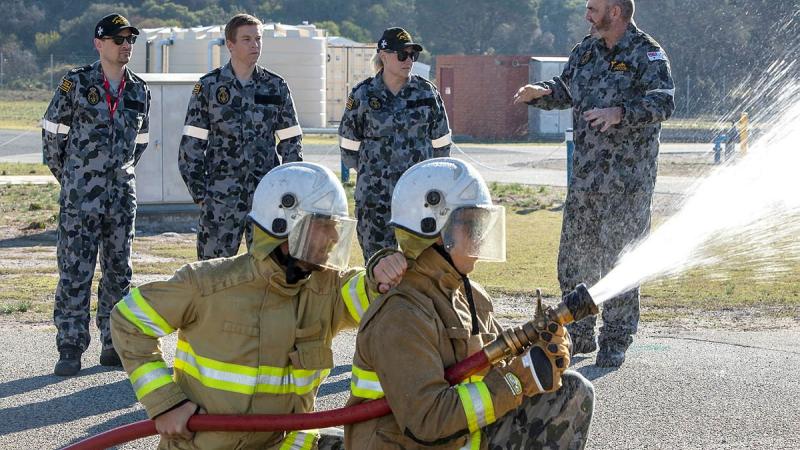 Senator for Victoria, Senator Raff Ciccone, Member for Ryan, Julian Simmonds and Senator for NSW Senator Hollie Hughes listening to Senior Instructor Chief Petty Officer Bryce Jackson explain fire hose techniques. Photo: Petty Officer Yuri Ramsey