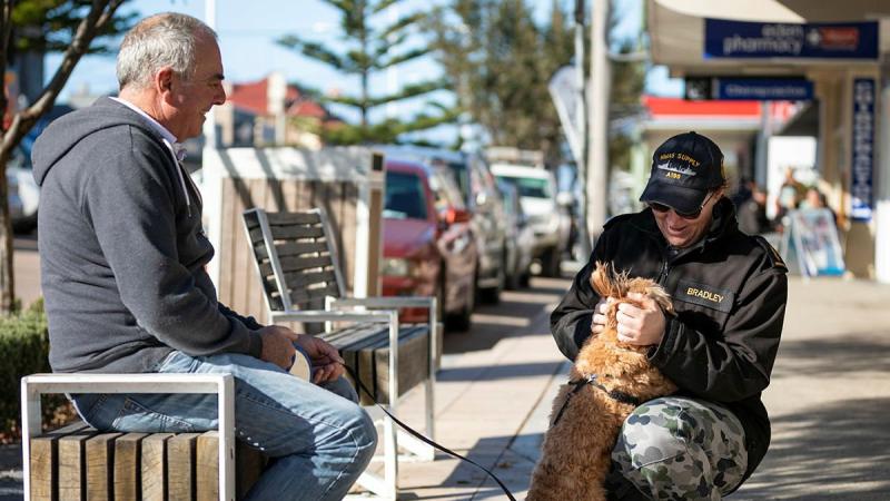 Able Seaman Tegan Bradley pats an Eden resident’s dog during the ship’s company’s walk into the NSW town during a port visit. Photo: Leading Seaman Daniel Goodman