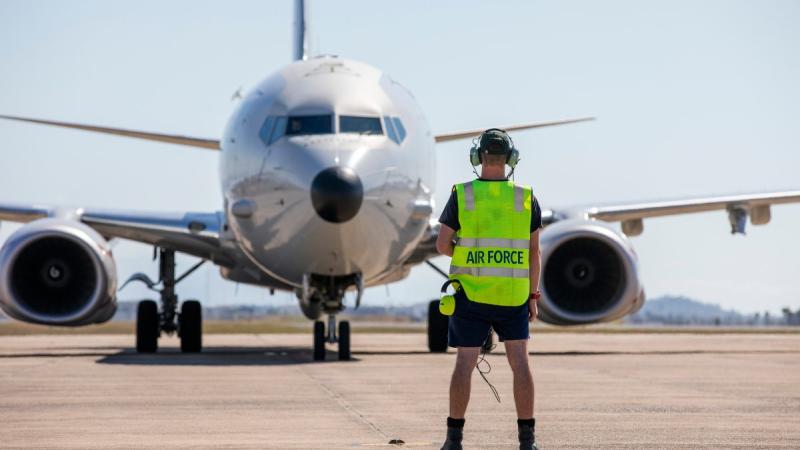 A Royal Australian Air Force Avionics Technician guides a P-8A Poseidon aircraft into position, as it prepares to depart RAAF Base Townsville in Queensland, during Exercise Talisman Sabre 2021. Photo: LACW Emma Schwenke