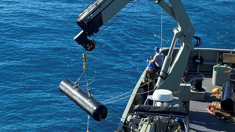 Personnel from HMAS Melville use a crane to lay an inert dummy mine off the coast of Queensland as part of Exercise Talisman Sabre.