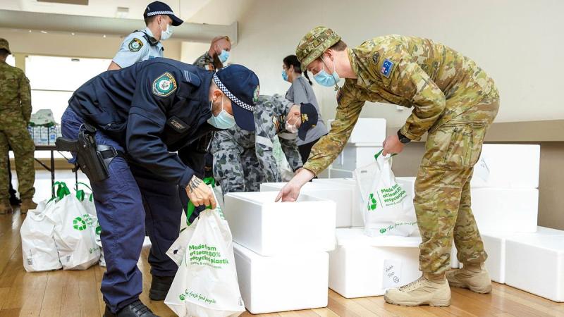 NSW Police and ADF members prepare to deliver pre-made meals as part of care packages given to homes in the Fairfield community in Sydney. Photo: Corporal Dustin Anderson
