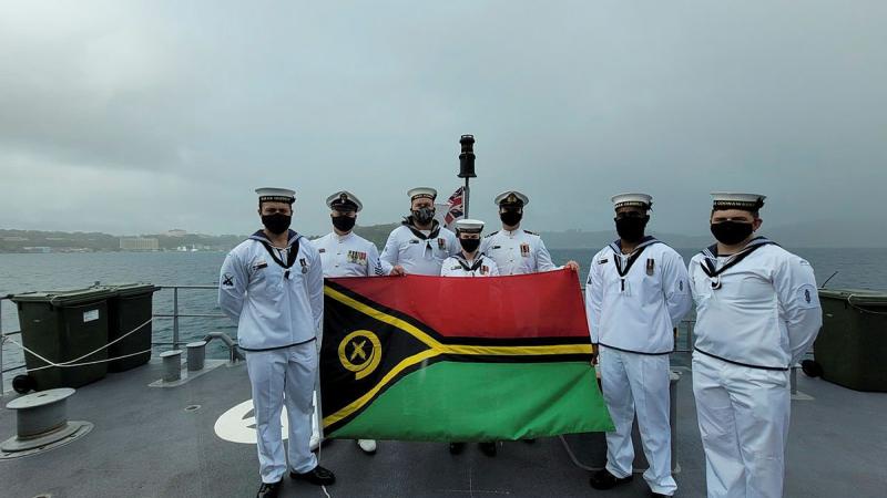 Personnel from HMAS Glenelg, with Commanding Officer Lieutenant Commander Alexander Finnis, third from right, display the Vanuatu flag while at anchor at Port Vila during Vanuatu's Independence Day celebrations.