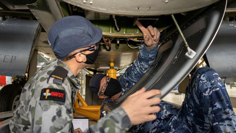 Corporal Andrew Ashbrook, right, helps avionics technician trainee Seaman William Cook to identify, recover and install a faulty voltage regulator.